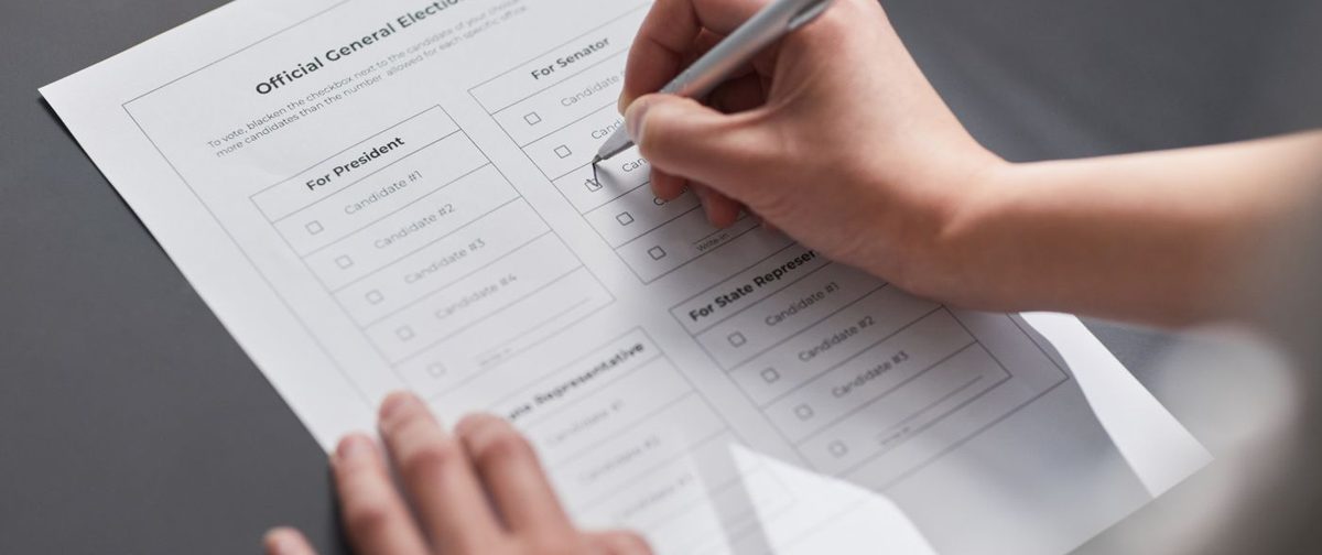 Una mano segna una scheda elettorale con la penna